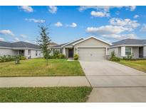 Single-story home with attached garage and landscaped lawn at 2311 Sunset Way, Davenport, FL 33837