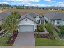 Single-story home with gray siding, a large driveway, and landscaping at 2597 Mariotta Rdg, Clermont, FL 34715