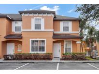 Two-story townhome with orange exterior, white trim, and landscaping at 2713 Impala Ln, Kissimmee, FL 34746