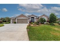 One-story home with three-car garage, lush landscaping, and a fountain at 3257 Triton Ct, The Villages, FL 32163