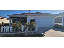 Charming home featuring a well-maintained front yard with a white picket fence and a convenient attached garage at 3621 Amelia Ave, The Villages, FL 32162