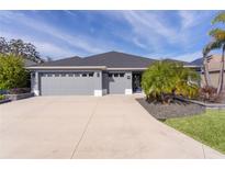 Gray three-car garage home with landscaped yard and palm trees at 4923 Lawler Loop, The Villages, FL 32163