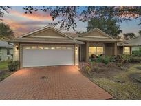 Tan one-story house with white garage door, brick driveway, and landscaping at 791 Princeton Dr, Clermont, FL 34711