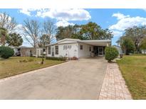 Single-wide manufactured home with carport and landscaped yard at 807 Maple Ln, The Villages, FL 32159