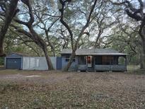 Cozy one-story house with covered porch and detached garage, nestled among mature trees at 10094 Sw 153Rd Ln, Dunnellon, FL 34432