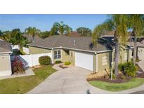 Single-story home with a green exterior, white garage door, and landscaped yard at 1418 Mccoll Ct, The Villages, FL 32162