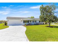 Charming single-story home features a well-manicured lawn and a concrete driveway leading to an attached two-car garage at 17664 Se 105Th Terrace, Summerfield, FL 34491