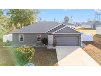 Charming single-story home with a well-manicured lawn, gray exterior and attached garage at 2555 Sw 154Th Place Rd, Ocala, FL 34473