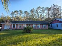 Brick ranch house with a spacious lawn and mature trees at 29 Lonesome Pine Trl, Yalaha, FL 34797