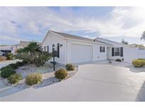 White house with two-car garage and landscaped front yard at 446 Flossmoor Ct, The Villages, FL 32162