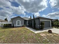 Charming single-story home boasts a manicured lawn and attached two car garage and welcoming walkway at 5756 Lakeside Landings Blvd, Winter Haven, FL 33881