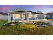 Gray house with a white porch and landscaping at 6764 Mary Loop, The Villages, FL 34762