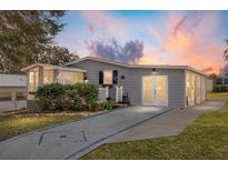 Updated manufactured home with a gray exterior, new landscaping, and a paved driveway at 1404 Torrey Pines Dr, The Villages, FL 32159