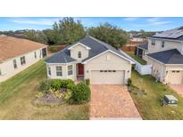 One-story home with a gray roof, red door, and landscaped yard at 16792 Meadows St, Clermont, FL 34714