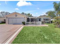 House exterior featuring a two-car garage and a well-manicured lawn at 17744 Se 95Th Ct, Summerfield, FL 34491