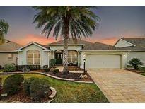 Charming single-story home with a large palm tree, manicured lawn, and paver driveway at 2709 Astoria Ave, The Villages, FL 32162