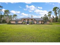 Stunning single-story home featuring mature trees, a lush lawn, and an elegant entrance at 29319 Old Mill E, Tavares, FL 32778