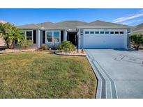 Single-story home with gray siding, white garage door, and landscaped lawn at 5570 Parkyn Path, The Villages, FL 32163