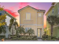 Tan three-story house with light-colored accents, landscaping, and palm trees at 8059 Knee Deep Rd, Kissimmee, FL 34747