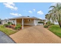 Charming single story home with a covered carport and a long driveway, plus mature tropical landscaping at 13 Sunrise Trl, Fruitland Park, FL 34731