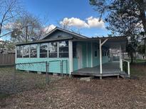 Charming blue house featuring a covered porch, a fenced yard, and sunroom windows at 13369 Cr 719, Webster, FL 33597