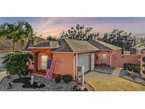 Attractive single-story home with a peach-colored exterior, American flag, and well-maintained landscaping at 1504 Aalto Pl, The Villages, FL 32159