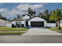 White house with dark gray garage door, landscaping, and a palm tree at 2320 Blue Meadows Ct, Apopka, FL 32703