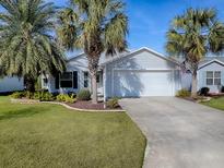 House exterior featuring a two-car garage and palm trees at 2549 Buttonwood Run, The Villages, FL 32162