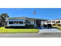 White single-story home with carport and golf cart, landscaped lawn at 106 Gardenia Way, Leesburg, FL 34748