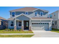 Two-story house with gray siding, stone accents, and a two-car garage at 1304 Silo Dr, St Cloud, FL 34771