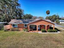 Orange one-story house with a well-maintained lawn and landscaping at 1415 Park Ave, Tavares, FL 32778