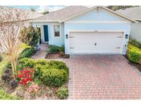 Curb appeal abounds in this charming one-story home, showcasing a brick paver driveway and well-manicured landscaping at 17313 Blazing Star Cir, Clermont, FL 34714