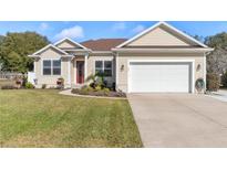 Charming single-story home with well-maintained lawn, landscaping, and a bright red front door at 177 Boardman Dr, Umatilla, FL 32784