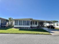 Charming manufactured home featuring a sunroom, carport, and well-maintained lawn at 188 Hibiscus Way, Leesburg, FL 34748