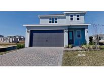 Two-story house with gray garage door and paved driveway at 2295 Juniper Berry Dr, Minneola, FL 34715