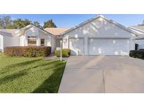 White house with two-car garage and well-manicured lawn at 2507 Caribe Dr, The Villages, FL 32162