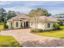 Tan house with a three-car garage and landscaped yard at 5312 Meadow Hill Loop, Lady Lake, FL 32159