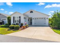 White single-story home with two-car garage and landscaped front yard at 5867 Marsh Ct, The Villages, FL 32163