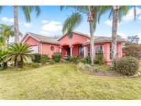 Pink stucco home with palm trees, fountain, and landscaped yard at 1130 Meadowbend Dr, Leesburg, FL 34748