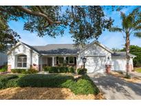 White brick home with gray roof, two-car garage, and landscaped yard at 1307 Lopez Ln, The Villages, FL 32159