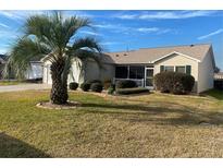 Tan one-story house with screened porch, palm tree, and well-manicured landscaping at 2171 Lewiston Ln, The Villages, FL 32162