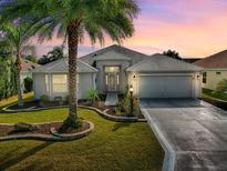 Charming single-story home featuring a well-manicured lawn, a two-car garage, and complemented by a mature palm tree at 320 Rhapsody Path, The Villages, FL 32162