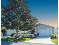 Charming home with a well-manicured lawn, mature tree, and a white picket fence at 433 Aldrich Ave, The Villages, FL 32162