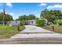 Single-wide home with circular driveway, landscaped yard, and American flag at 705 Devon Dr, Lady Lake, FL 32159