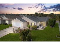 Charming home exterior featuring a manicured lawn, landscaped beds, and screened patio at 893 Fenwick Loop, The Villages, FL 32163