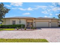 Lovely home with a brick driveway, trimmed bushes, a black iron gate, and a three-car garage at 917 Shorehaven Dr, Poinciana, FL 34759