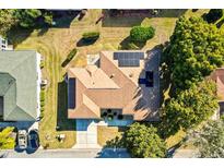 Aerial view of a charming home, featuring a brown roof and lush green surroundings with solar panels at 9184 Se 135Th St, Summerfield, FL 34491