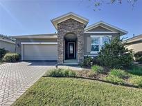 Charming single-story home with stone facade, two-car garage, landscaped yard, and brick-paved driveway at 96 Silver Maple Rd, Groveland, FL 34736