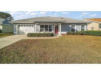 One-story home with gray exterior, white garage door, and red front door at 11579 Se 172Nd Loop, Summerfield, FL 34491