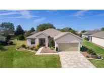 Charming single-story home with landscaped front yard and patterned driveway, offering great curb appeal at 13914 Se 96Th Cir, Summerfield, FL 34491